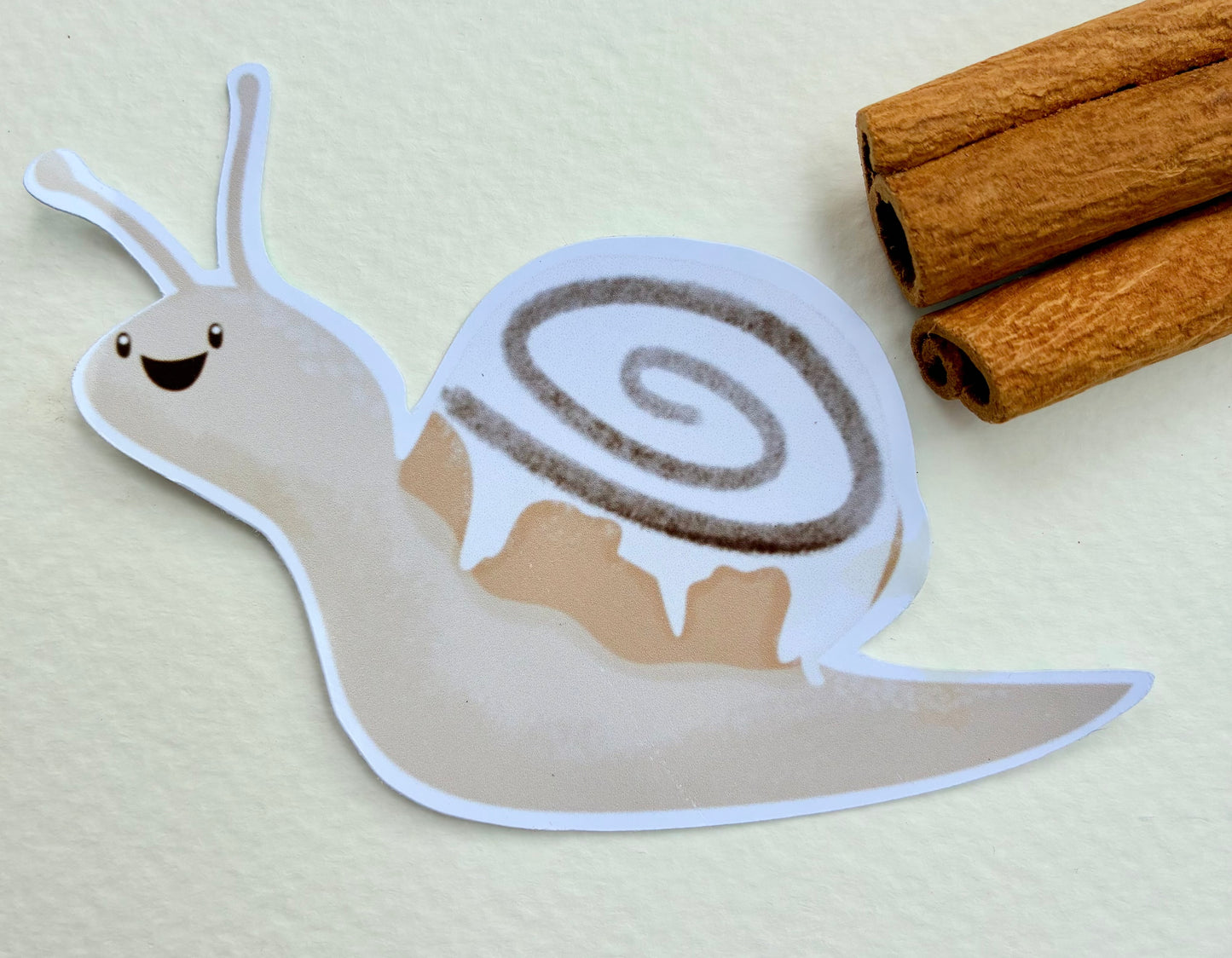 Snail sticker with a cinnamon bun shell with cinnamon sticks in the background
