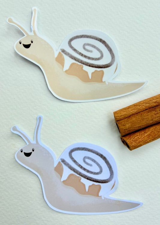 Two snail stickers with cinnamon bun shells with cinnamon sticks on a light background