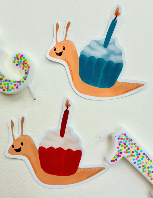 two snail stickers with cupcake shells in blue and red, both have birthday candles in them